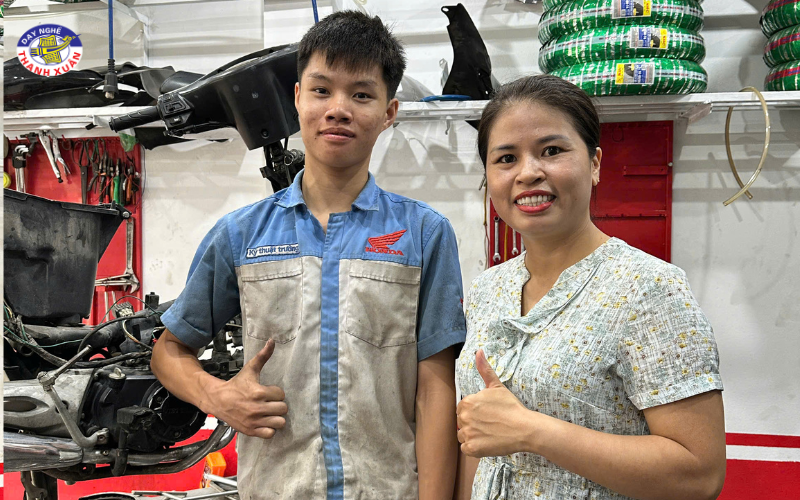 Cô giáo không quản ngại lấm bẩn, đến tận bàn nâng thao tác để hỏi thăm công việc, mức lương và những khó khăn của học sinh mới ra nghề.